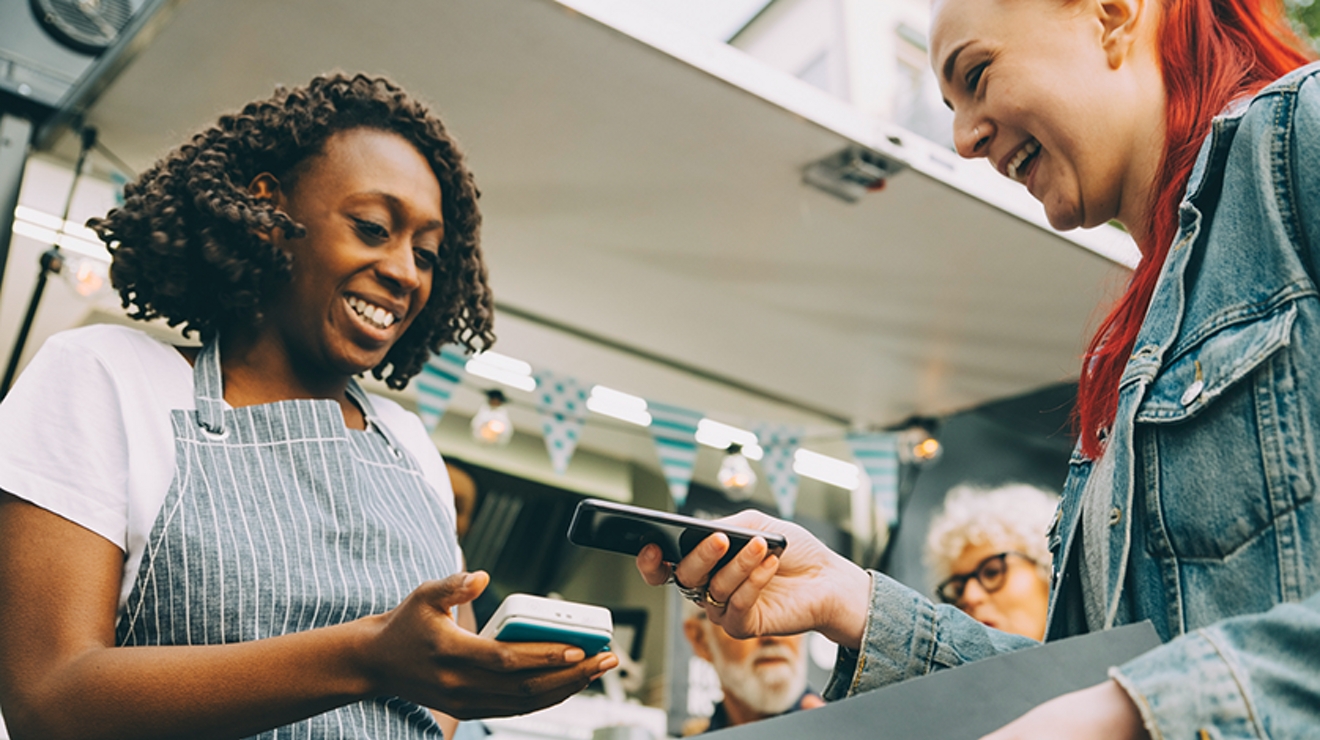 Empleada de una tienda usando un dispositivo móvil para que el cliente pague con su smartphone