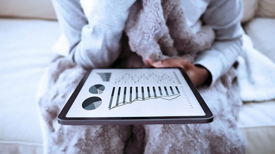 Mujer relajándose en bata y mirando su tablet.