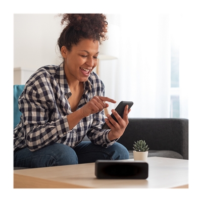 Una mujer sentada en el sofá usando su teléfono.